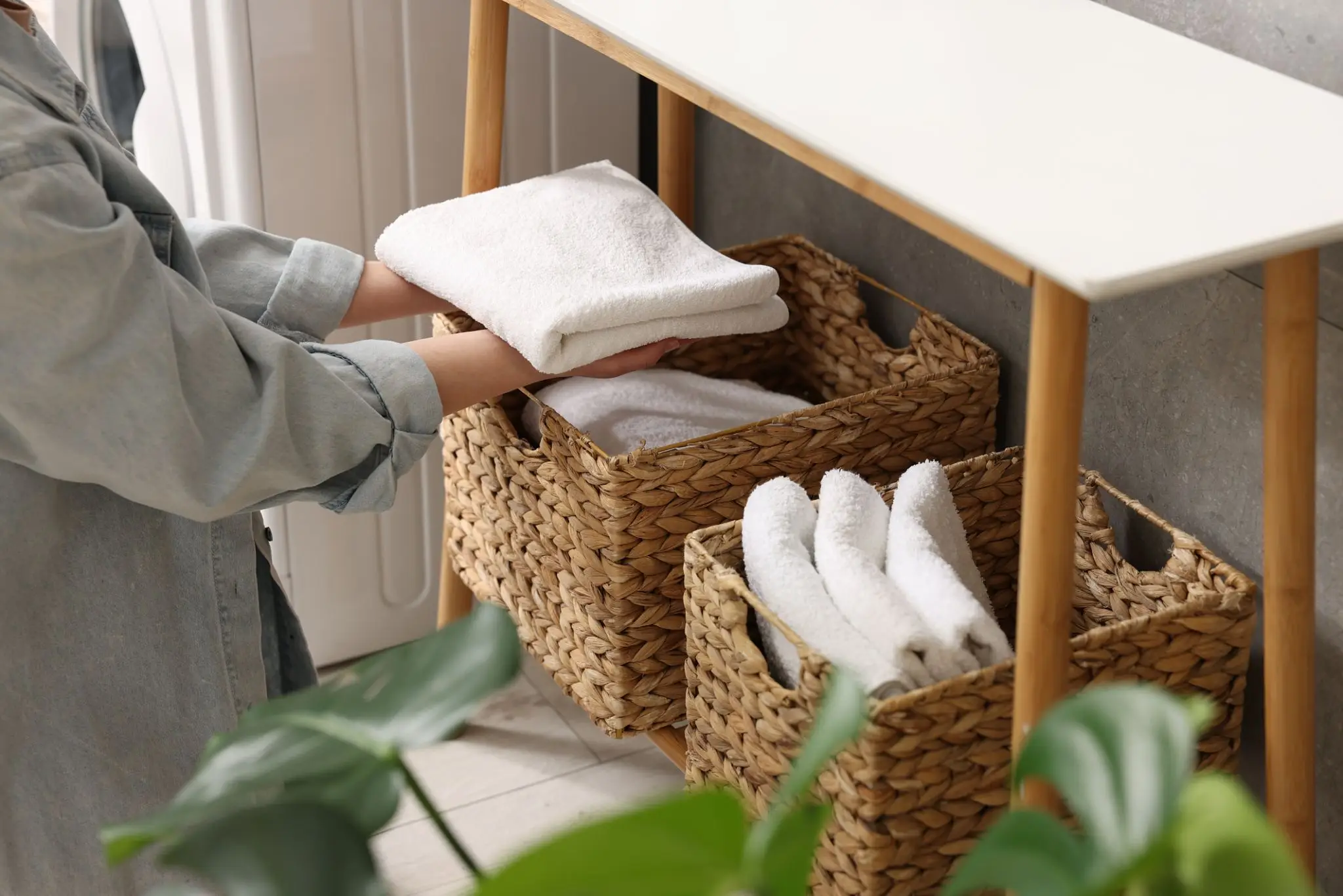 Person organizing towels in woven baskets.