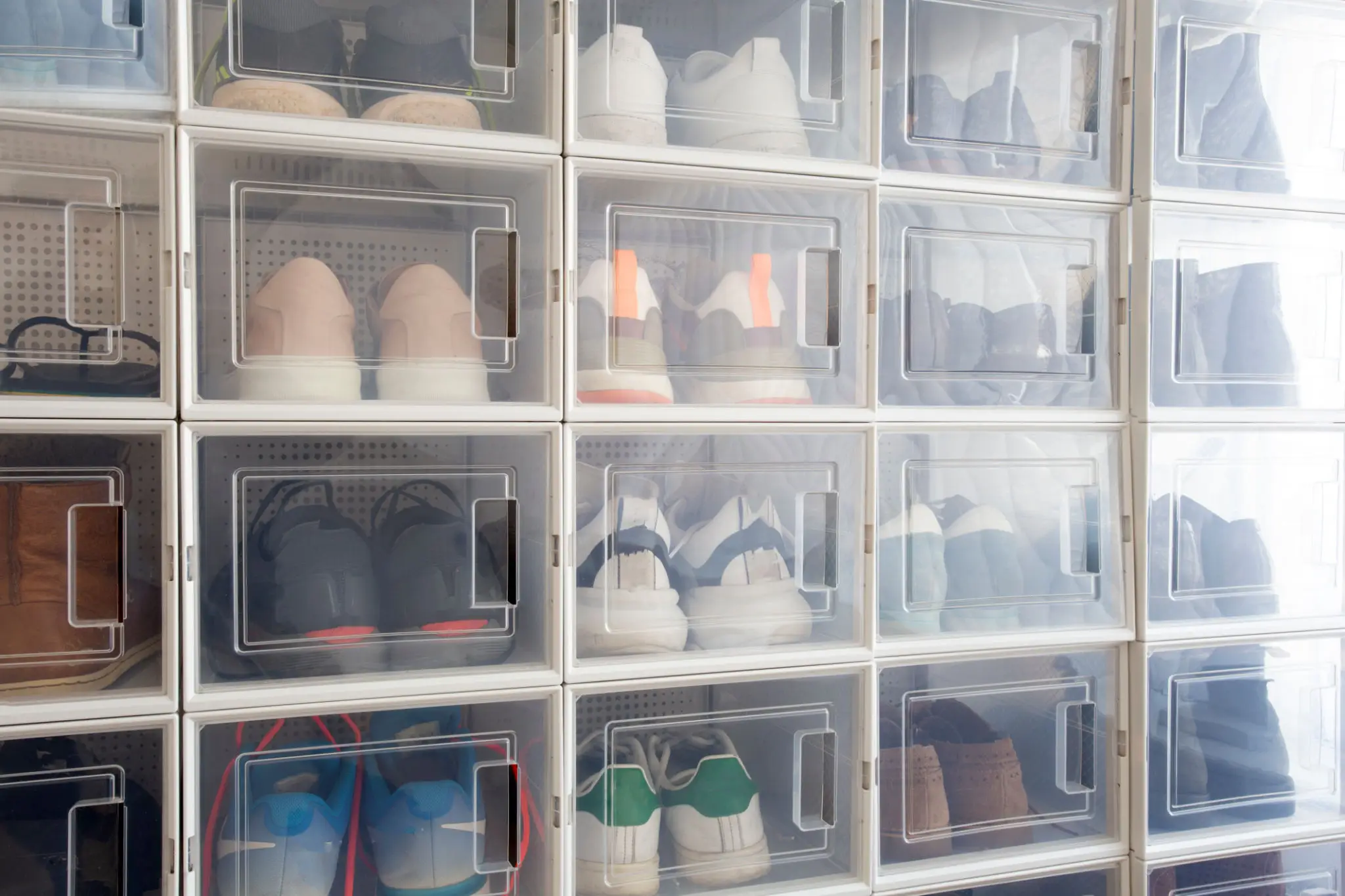 Stacked clear boxes with various shoes inside.